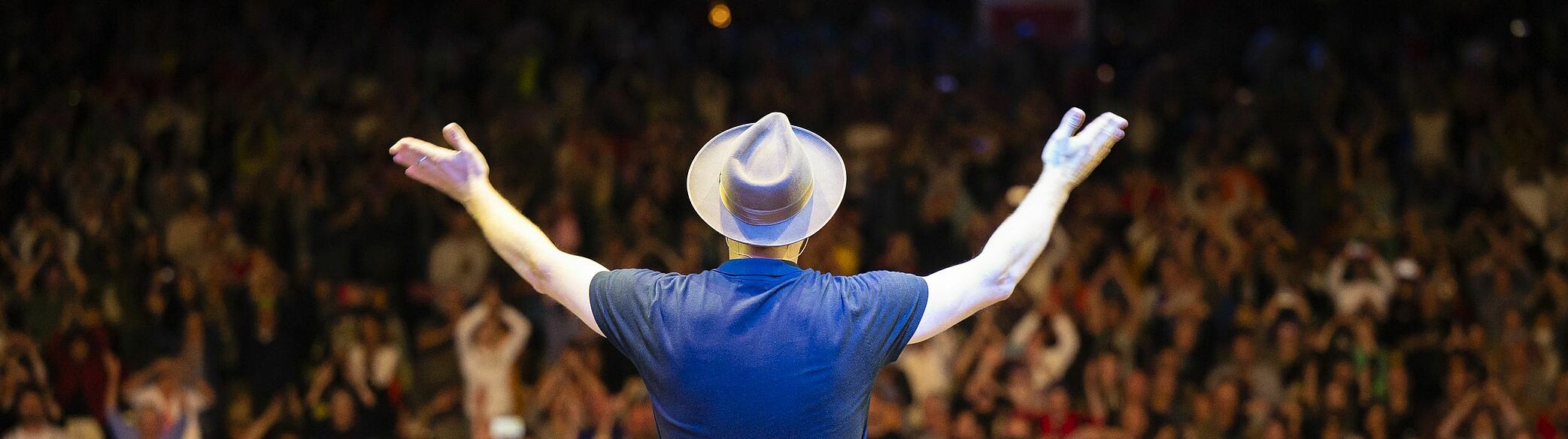 Mann mit geöffneten Armen vor Publikum